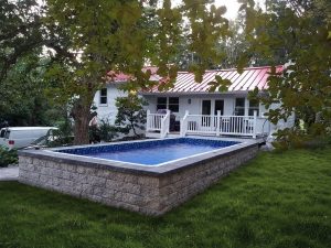 A pool in the middle of a yard with trees.