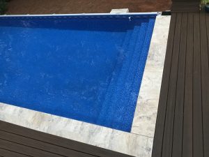 A pool cover is being installed on the side of a deck.