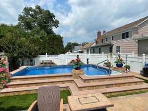 A pool with steps leading to the back yard.