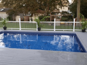 A pool with a fence around it and trees in the background.