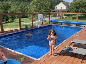 A girl in a pink bikini standing next to an above ground pool.