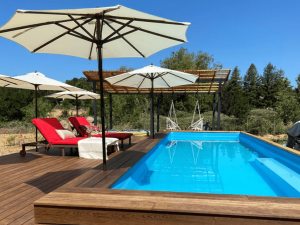 A pool with an umbrella and chairs on the deck