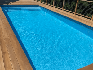 A pool with wooden deck and blue water