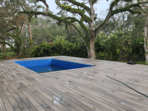 A pool is in the middle of an outdoor deck.