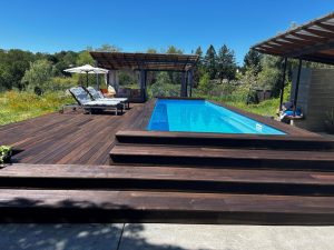 A pool with wooden steps and a deck